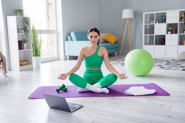 照片甜美闪亮的女孩穿着运动服坐在垫子上看视频瑜伽课在家里的房子图片下载