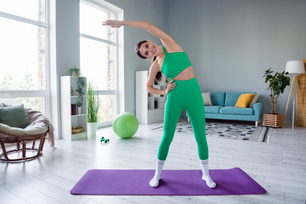 迷人苗条的女士穿着运动装微笑伸展回到室内家庭工作室的全长照片图片下载