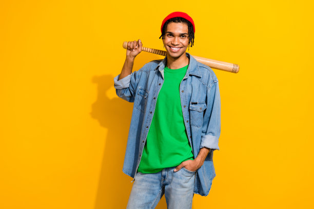 照片正面有吸引力的家伙街头流氓穿着时尚的牛仔衣服持有棒球棒孤立的黄色背景图片下载