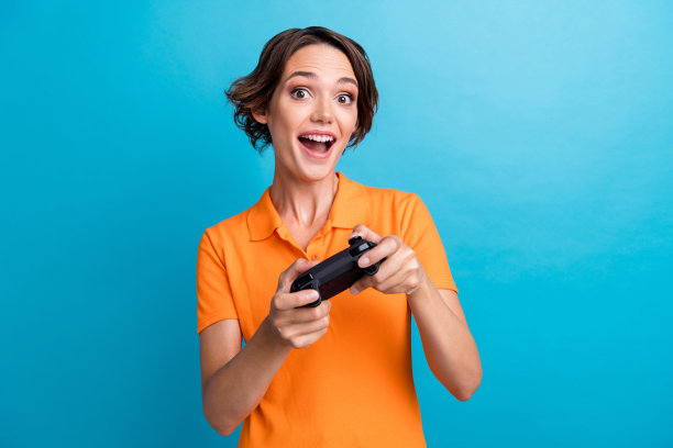 快乐的女孩身穿橙色Polo衫玩PlayStation游戏照片图片下载