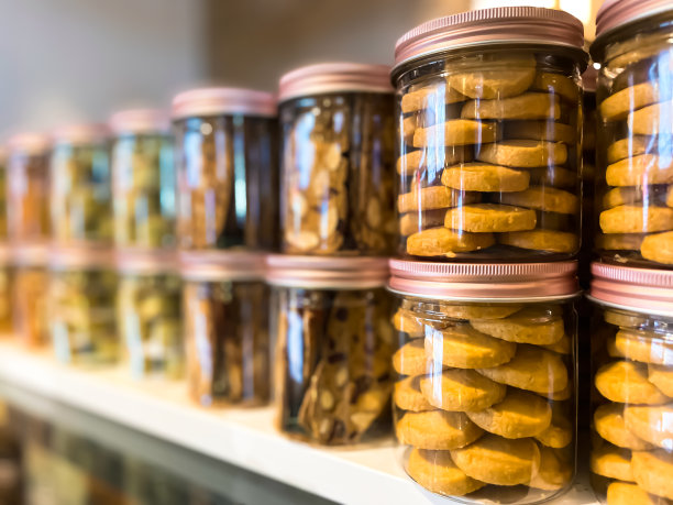 许多玻璃罐与瓶盖装满饼干在散焦的背景与反射。自助餐厅或餐厅的背景。小企业的概念。图片下载