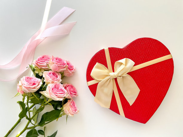 礼品盒的形状是心形的，在浅色的背景上有鲜花和丝带。情人节，母亲节，生日，三八，妇女节，卡片图片下载
