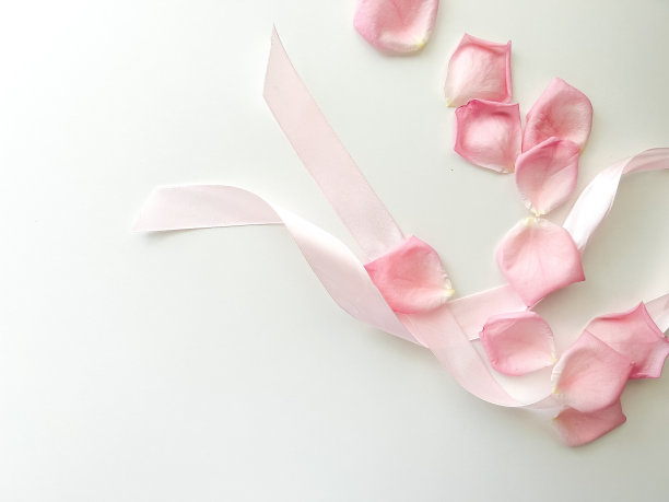 粉红色的丝带和玫瑰花瓣在浅色的背景。放文字的地方。情人节、母亲节、生日、三八节、妇女节、卡片图片下载