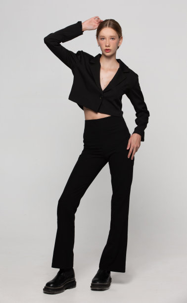 漂亮苗条的女孩模特穿着经典的黑色西装。一个美女在灰色背景上的垂直照片。图片下载