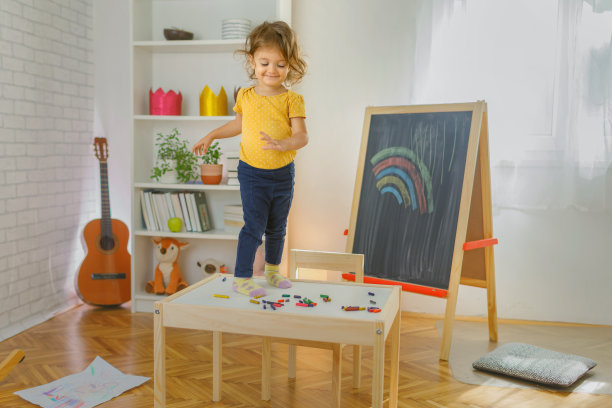 年轻的女孩微笑着站在椅子上，手里拿着一幅画。图片下载