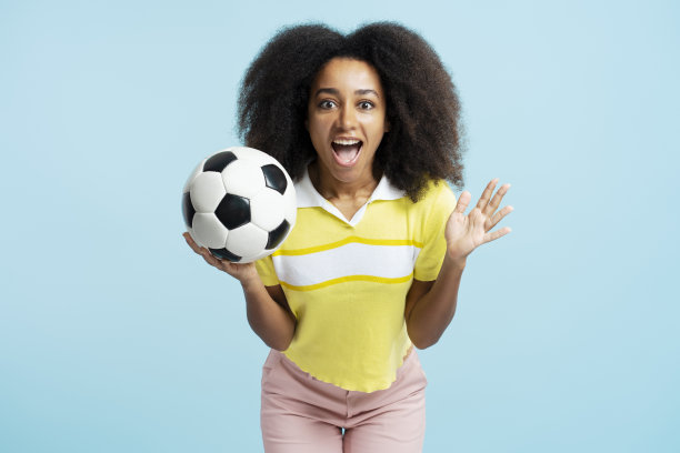肖像激动迷人的非洲裔美国妇女拿着足球，穿着休闲服图片下载