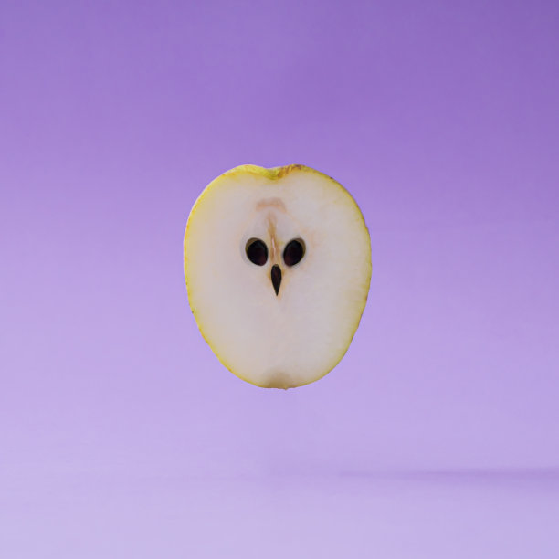 猫头鹰还是梨子。在柔和的紫罗兰色背景上用黄色梨做成的猫头鹰脸的创意布局。极简超现实的食物概念。有趣的甜水果的想法。梨审美背景。图片下载