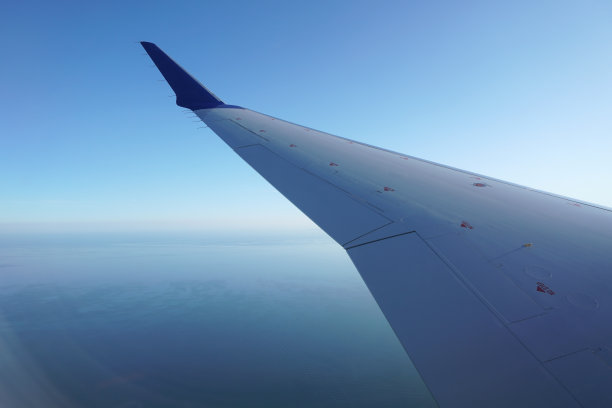 商务飞机的机翼视图在波罗的海上空飞行在晚上图片下载