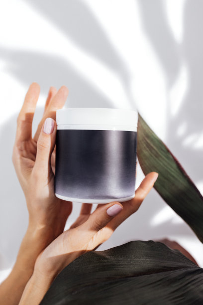 年轻女性正在享受美容护理。女孩手里拿着一瓶面霜或凝胶图片下载