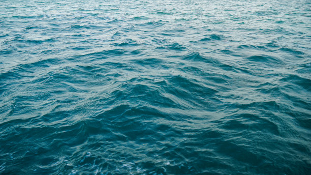 蓝绿色海水的俯视图。比如背景。小波浪在海面上激起涟漪，改变颜色。在某些地方从青绿色渐变到深蓝色。干净的海洋。背景照片。图片下载