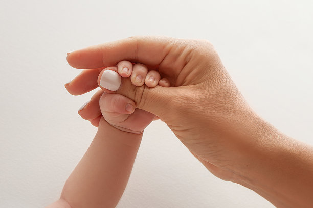 父母的手握着新生婴儿的手指。一对父母的手握着一个新生婴儿的拳头(特写)。家庭保健和医疗保健。白色背景的专业照片图片下载