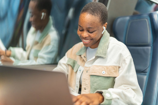 可爱的非裔美国学生在火车上使用笔记本电脑，在窗户上复制空间，商务旅行或技术概念。图片下载
