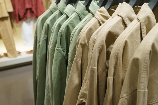 一家服装店的衣架上挂着绿色和棕色的长袖衬衫。图片下载