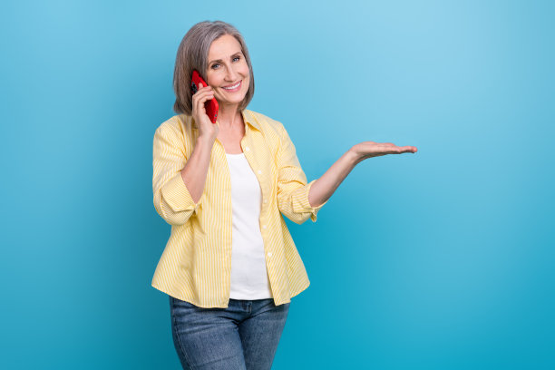 照片正面甜美的女人穿着黄色衬衫说话现代小玩意抱着手臂空的空间孤立的蓝色背景图片下载