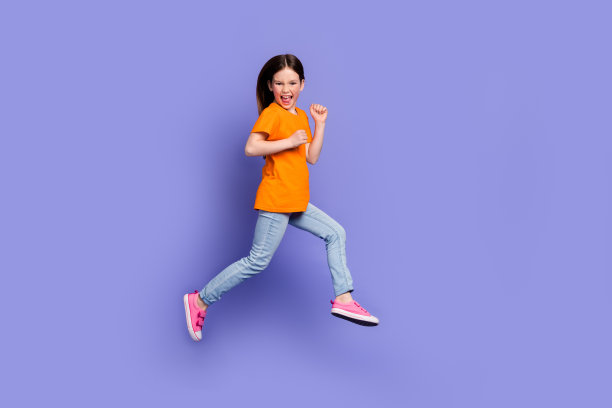 有趣的正面学生穿着橙色t恤的全长照片，匆忙跑到空旷的空间，孤立的紫色背景图片下载