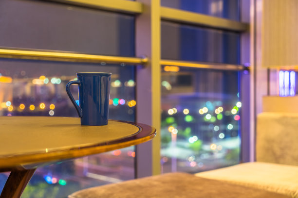 晚上窗边桌子上的蓝色咖啡杯图片下载