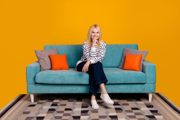 照片积极的女士觉得周到的购买蓝色舒适沙发隔离在明亮的颜色背景图片下载