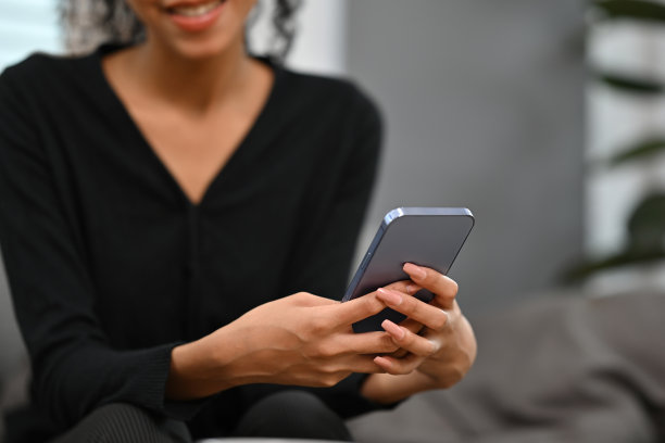 一位迷人的年轻非洲女子白天坐在客厅里玩手机的特写图片图片下载