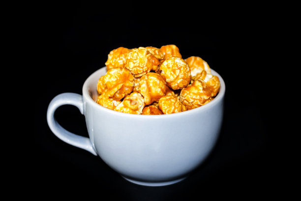 特写图片爆米花上的杯子与黑色的背景颜色。图片下载