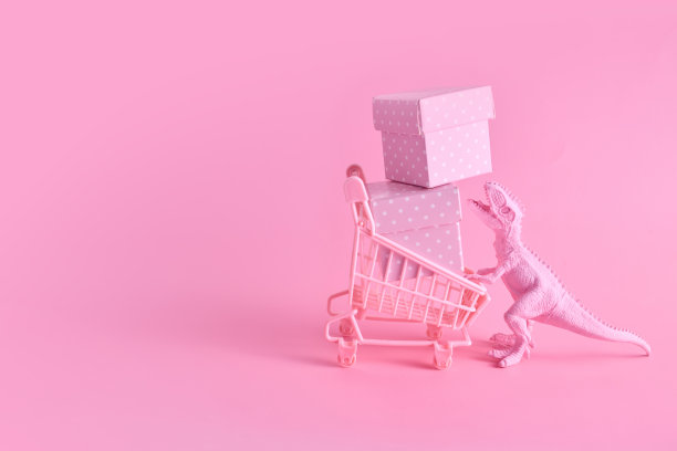 粉色星期五的概念。有趣的粉红色恐龙玩具与购物车满是礼物盒粉红色的背景图片下载