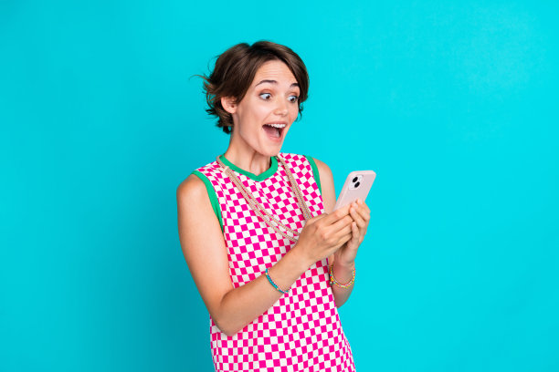 年轻有趣的照片惊讶鲍勃棕色头发的女士震惊地看着她的手机电子银行收到的钱孤立的海蓝宝石色背景图片下载