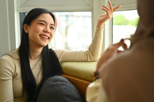 两个年轻的女性朋友在家里的沙发上喝咖啡聊天的照片图片下载