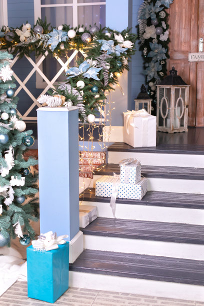 节日户外设计，在院子里有圣诞树和礼物。房子的入口楼梯装饰着冬天的节日，礼物，树枝冷杉和发光的花环。舒适的木质门廊的房子与礼物图片下载