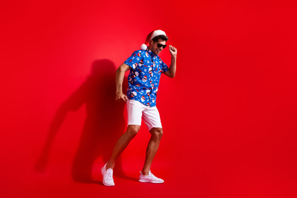 全身照片英俊的年轻男子舞者有乐趣迪斯科舞厅穿圣诞老人印刷圣诞服装孤立的红色背景图片下载