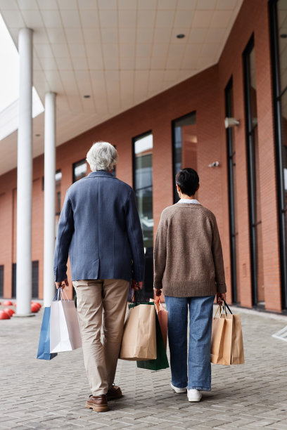 老夫妇提着购物袋一起走在商场外面图片下载