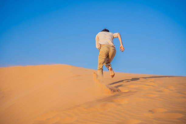 这个人克服困难，追求目标和梦想。一个人克服生活中的困难就像在沙漠中一样图片下载