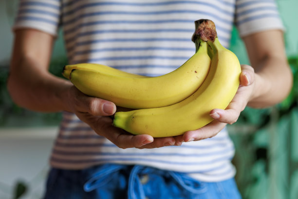 照片中，一名女子手持一串熟香蕉，露出了她的腹部。图片下载
