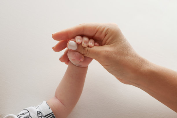 父母的手握着新生婴儿的手指。一对父母的手握着一个新生婴儿的拳头(特写)。家庭保健和医疗保健。白色背景的专业照片图片下载