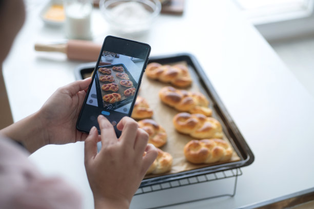 女性烘焙厨师或面包师使用她的智能手机手机拍摄新制作的面包照片，并将照片发送到社交媒体，烹饪和烘焙概念，自制烘焙小生意图片下载