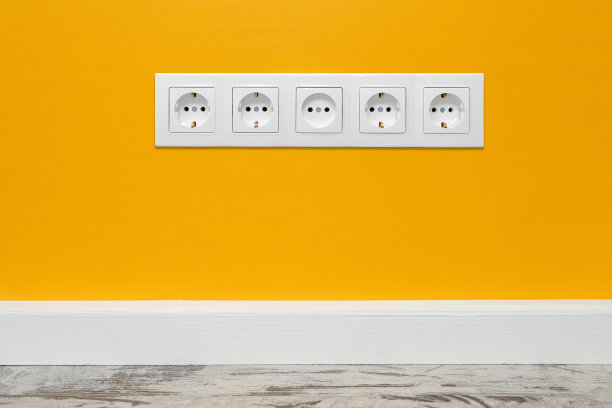 白色五通墙电源插座在黄色墙上图片下载