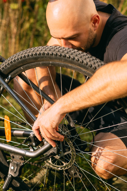 一个人拿着他的山地车车轮并修理它的高角度视图。图片下载