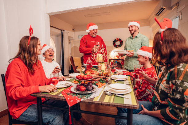 阖家欢乐笑口常开欢度圣诞，举杯共饮美酒。家庭成员在家里享用自制的烤火鸡大餐。图片下载