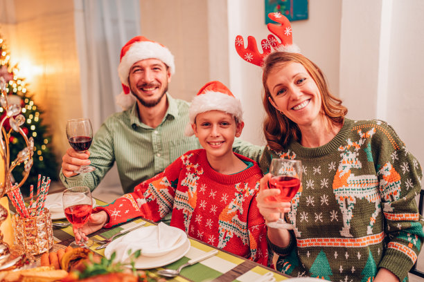 阖家欢乐笑口常开欢度圣诞，举杯共饮美酒。家庭成员在家里享用自制的烤火鸡大餐。图片下载