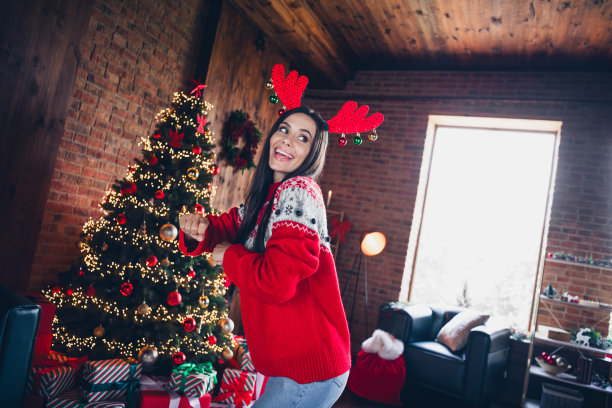 穿着红色毛衣的开朗、凉爽、快活的女孩在室内独自跳舞的圣诞早晨主题派对照片图片下载
