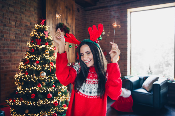 照片肖像可爱的黑发女郎迪斯科抱孟加拉灯穿着装饰毛衣新年温馨的家室内圣诞树图片下载