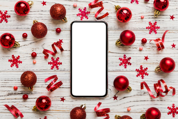 圣诞节网上购物从家里电话与空白白色显示顶视图。智能手机与彩色背景上的复制空间与圣诞装饰球，。寒假销售背景图片下载