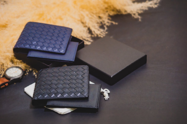 高品质真皮钱包分离式，里面可以装卡片，黑色背景，旁边放着黄色的干草花。工作室拍摄促销产品图片图片下载