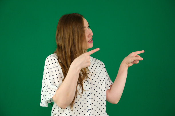 工作室拍摄的年轻超重美女。漂亮的女人带着幸福的脸微笑着看着，用手指指着白色背景上孤立的一边图片下载