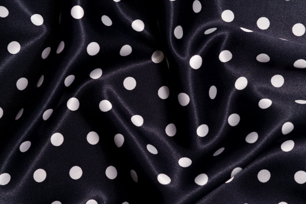 纹理皱巴巴的黑色织物与白色圆点特写。图片为您的设计。缝制衣服用料图片下载