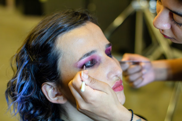 年轻女子在镜子前为晚上的约会化妆(画睫毛)。关注她的倒影图片下载