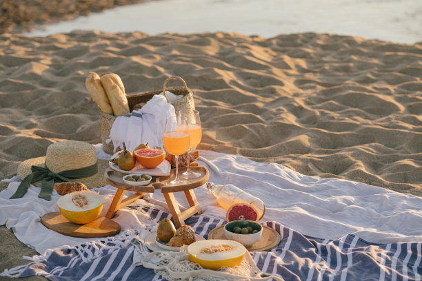 美丽美味的野餐，柠檬水，新鲜水果和牛角面包在日落的海滩。图片下载