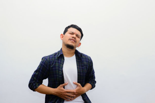 亚洲人抱着他的肚子感觉很胃痛孤立在白色的背景。工作室的照片。健康的概念。图片下载