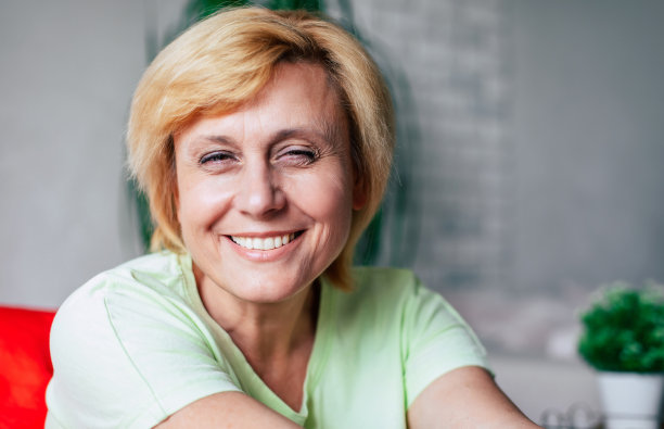 中年成熟的快乐兴奋的微笑女人在家里的沙发上穿着休闲服放松和大笑的特写照片图片下载