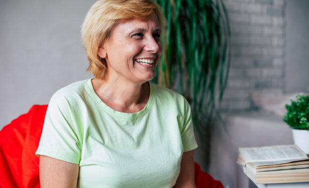 中年成熟的快乐兴奋的微笑女人在家里的沙发上穿着休闲服放松和大笑的特写照片图片下载