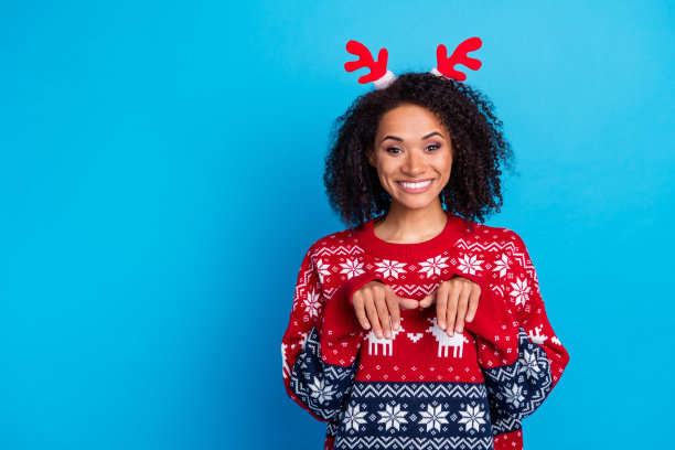 无忧无虑的人的照片，在圣诞派对上，戴着红色鹿角的女人露齿微笑，做着爪子的手势，背景是蓝色的图片下载