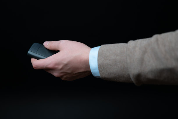 汽车销售员将新电动汽车的车钥匙交给买家。黑色背景的工作室环境。图片下载